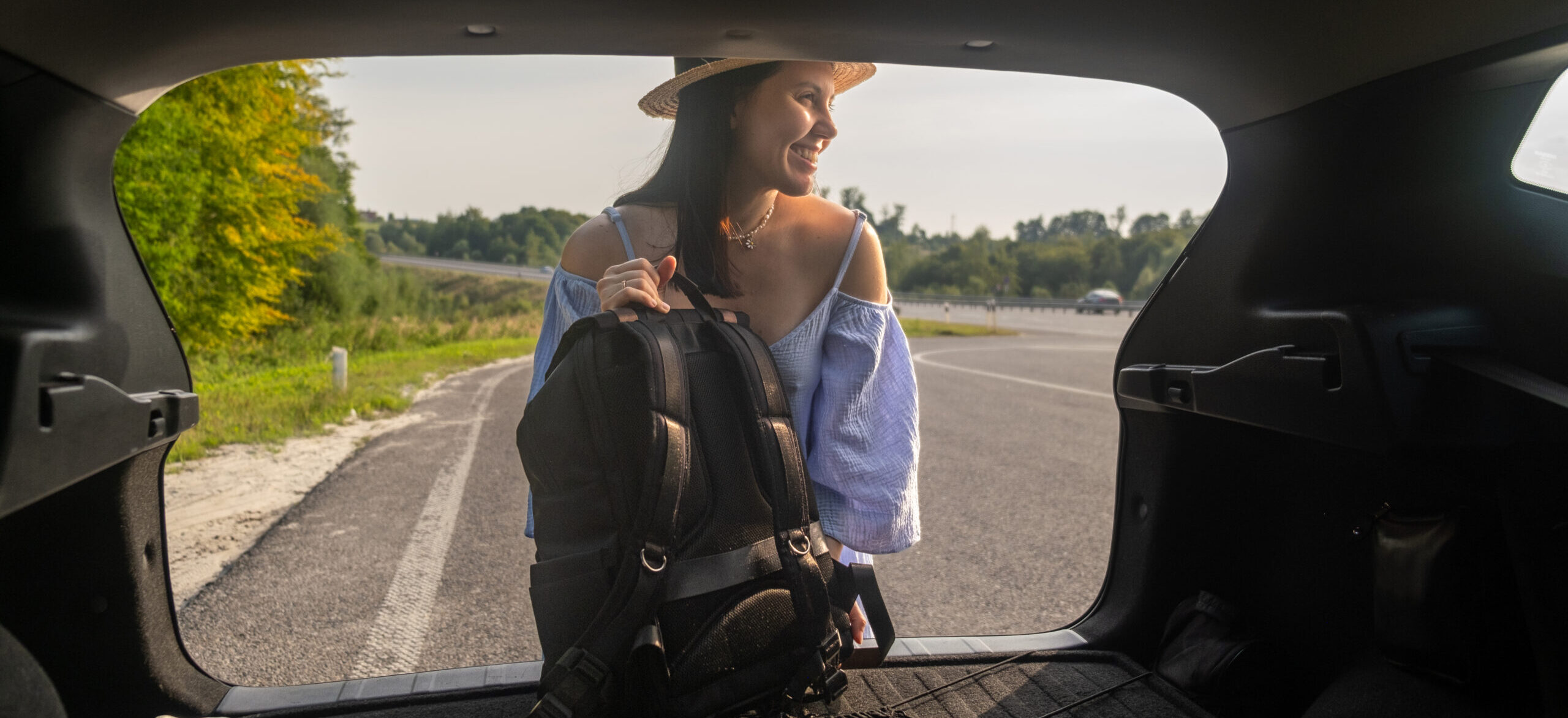 Autovermietung Zetex Rent A Car smiling woman with backpack by car scenic road scaled e1745587892699
